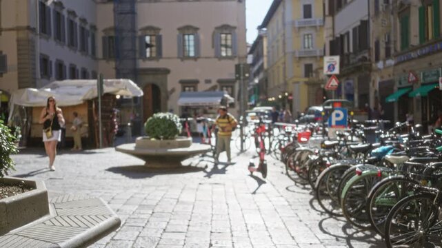 Florence plaza with cobblestone paving, fountain and rows of bikes softly blurred and defocused; background backplate copyspace calm.