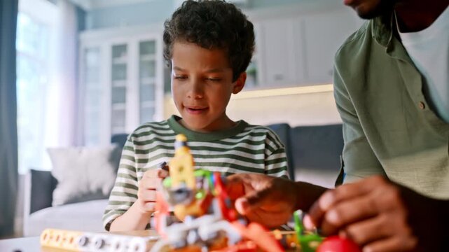 Boy assembling toy robot with father. Close up child hands building kit home.