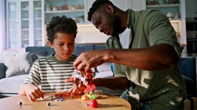 Multiethnic boy dad building robot toy construction kit. Family STEM play home.