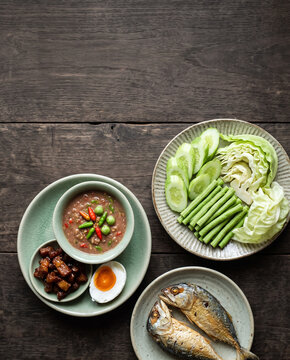 Thai nam prik long ruea shrimp paste relish with sweet pork, salted egg, fresh vegetables and fried mackerel, top view with copy space, vertical