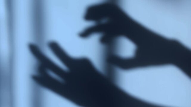 Creepy shadow of human hands with bent fingers moving behind a curtain. Dark horror scene with eerie silhouette, suspenseful atmosphere, fear, danger, and mystery. Perfect for themes of horror movies,