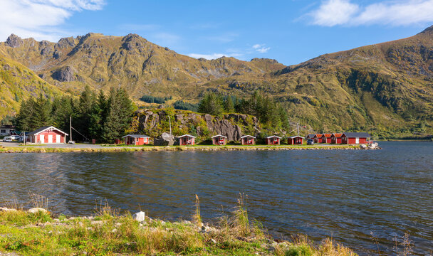 Traditional red cabins beside a fjord surrounded by mountains in the Lofoten Islands, Norway
