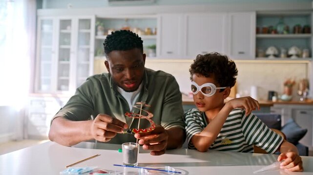 Father son home science experiment kitchen. Boy safety goggles watching candle.