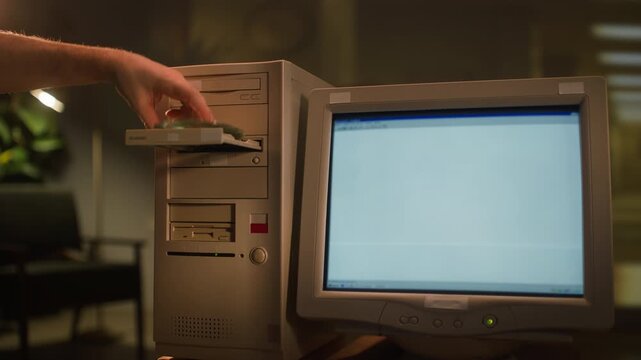 Retro computer tower close up, hand inserting floppy disk and opening CD ROM drive of old 90s desktop PC, vintage personal computer in office