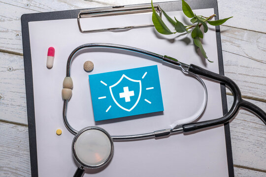 Healthcare Protection and Medical Safety Concept with Shield and Cross Symbol on Blue Note and Stethoscope.