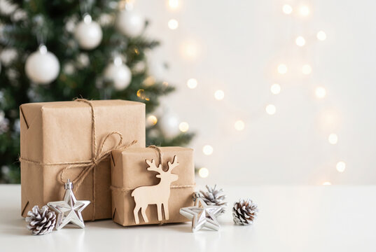 christmas and new year background - gift boxes and stars near decorated christmas tree and copy space over white wall with lights