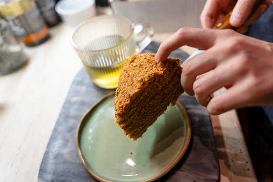 Hand Serving Delicious Layered Honey Cake Slice with Tea