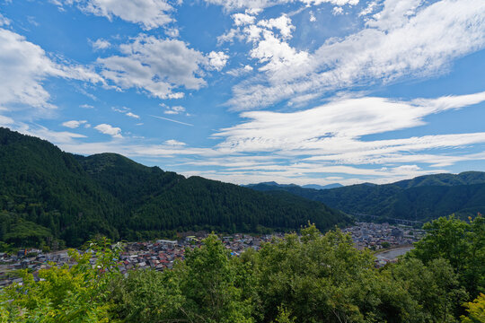 Valley Town and Forested Hills Beneath a Cloud Filled Blue Sky