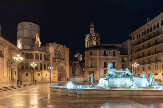 Valencia, Spain - night view of the illuminated Plaza de la Virgen in historic center with famous Turia Fountain (Fuente del Turia) with the historic Valencia Cathedral and Miguelete tower