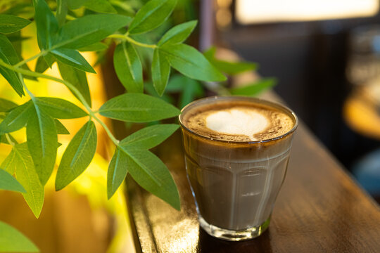Hot coffee latte with latte art milk foam in cup mug on wood desk on top view. As breakfast In a coffee shop at the cafe,during business work concept,vintage style