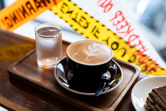 Hot coffee latte with latte art milk foam in cup mug with decor in a coffee and tiramisu cake decorated with cute edible eyeball  a theme of halloween on wood desk Halloween holiday background.