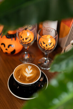 Halloween celebrated coffee,Close up of Hot coffee latte with latte art milk foam in cup mug with decor in a coffee a theme of halloween on wood desk Halloween holiday background.
