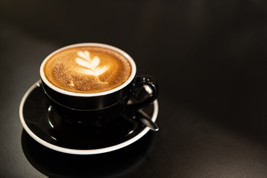 Hot coffee latte with latte art milk foam in cup mug on wood desk on top view. As breakfast In a coffee shop at the cafe,during business work concept,vintage style