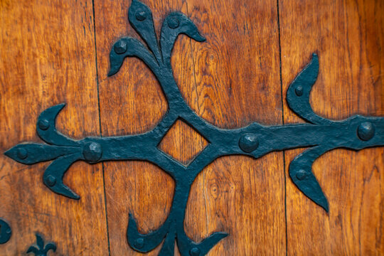 Close up detail of an old wooden door with decorative metal hinge