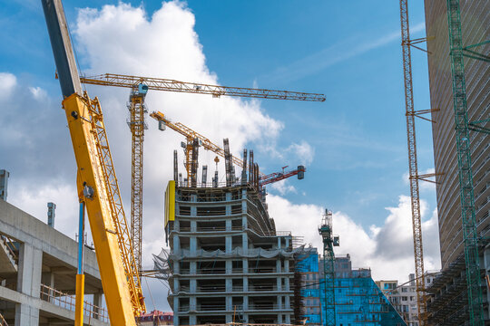 Construction site with tower cranes and mobile lifting equipment for skyscraper building development, urban growth, civil engineering and modern city infrastructure expansion