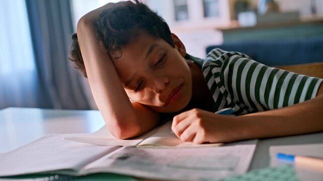 Close up exhausted teen boy resting head desk. Writing homework notebook home.