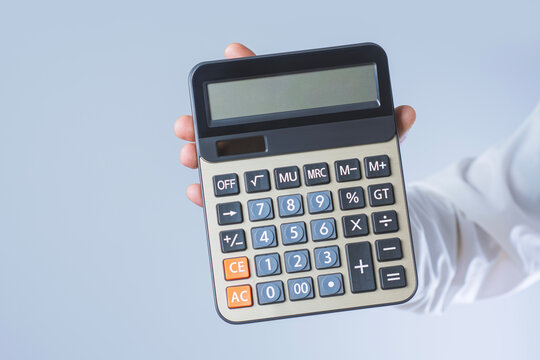 Hand holding calculator with blank display and copy space on light background. Financial calculation, accounting or business budget planning concept.