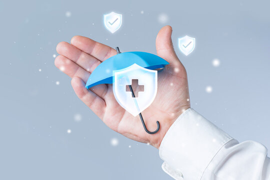 Businessman hand holding miniature umbrella with medical shield icon and checkmark symbols. Health insurance protection, medical coverage or risk management concept.