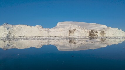 Massive Iceberg Reflected in Calm Water in Ilulissat Icefjord, Greenland © Yunxia