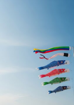 Vibrant colorful carp streamers sway gracefully in a soft spring breeze against a clear blue sky, evoking a sense of calm and serenity, textile, serenity, clouds