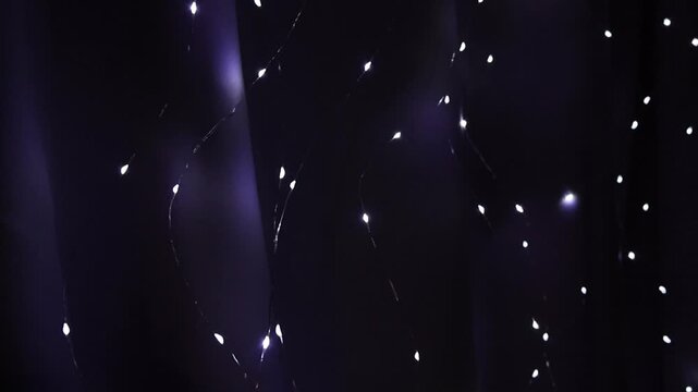 Flashing LED fairy lights garland changing blinking modes on draped curtain background