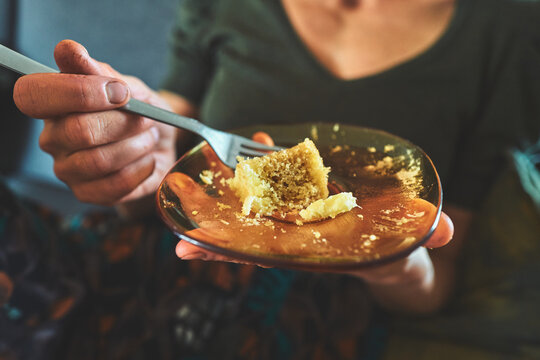 Woman Eating the Last Crumbs of Cake from an Amber Plate