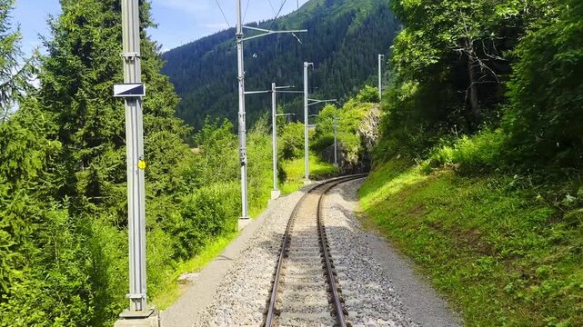 Front View on Glacier Express Train on Railroad Tracks and Mountainscape and Valley in a Sunny Summer Day in Sedrun, Surselva, Oberalp, Grisons, Switzerland