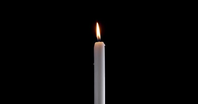 Lit taper candle on a black background. The golden flame of the candle slowly flickers. A minimalist candle for background or over-layer with blending mode screen, lighten, or add.