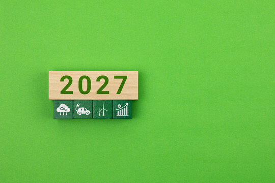 Stacked wooden cubes featuring green energy icons. 2027 as the year for the implementation of renewable energy. Isolated, with space.