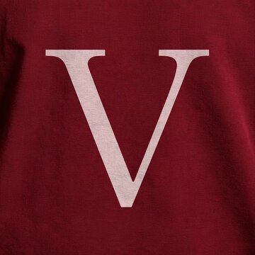 A large cream serif letter V is printed on the chest of a burgundy cotton shirt with soft fabric texture.