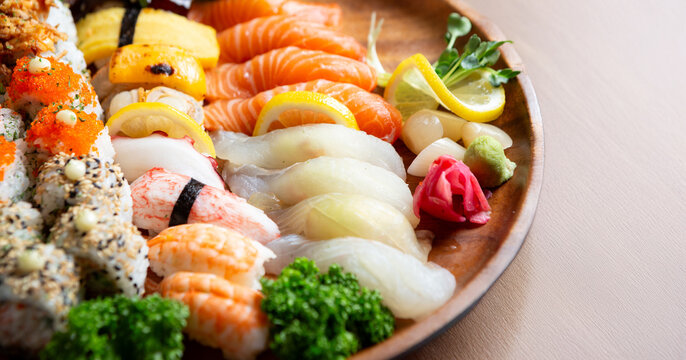 Gourmet Japanese assorted sushi platter with salmon, white fish, shrimp, tamago nigiri, and sushi rolls on a wooden tray