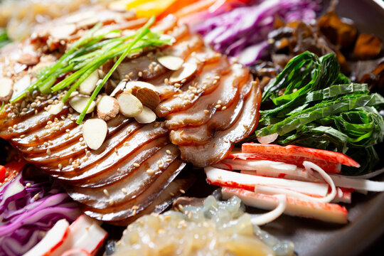 Gourmet Korean chilled trotter salad known as Naengchae-jokbal topped with almond flakes, chives, and assorted colorful vegetables