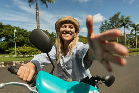 Joyful woman on a scooter rides toward the camera