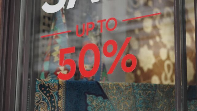 Store window displays a sale sign offering up to 50 percent off