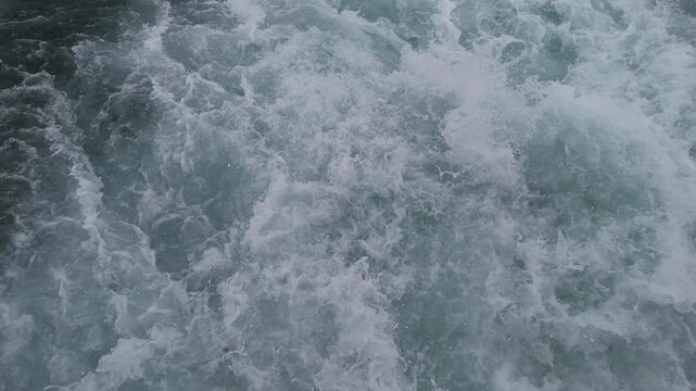 Ocean waves churn and break across the water during the day