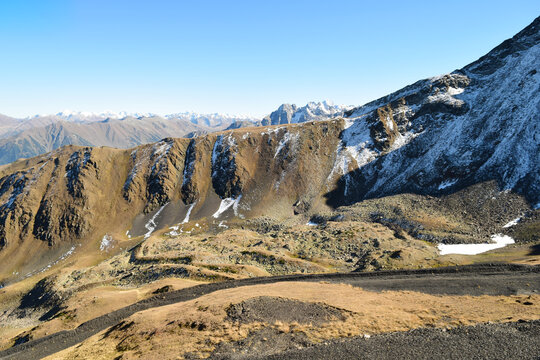 Steep cliff face with lingering snow and autumn grass
