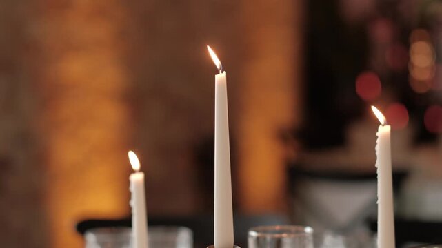 Three lit white taper candles glowing warmly on a dark background