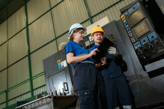 Two Heavy Industry Engineers Stand in Pipe Manufacturing Factory, Use Digital Tablet Computer, Have Discussion. Design and Construction of Large Oil, Electrical control cabinet. Low Angle