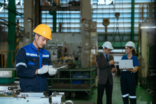 Two Heavy Industry Engineers Stand in Pipe Manufacturing Factory, Use Digital Tablet Computer, Have Discussion. Design and Construction of Large Oil, Electrical control cabinet.
