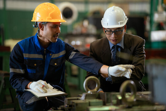 The supervisor inspected the metal parts and spoke with the technicians in the automotive parts manufacturing plant.
