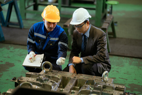 The supervisor inspected the metal parts and spoke with the technicians in the automotive parts manufacturing plant.