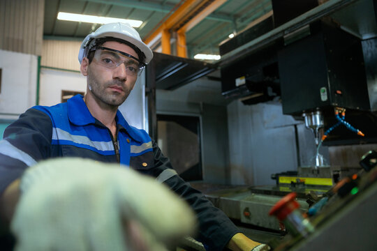 The technician is looking through a camera and pressing buttons on the control panel of a drilling machine in the factory.