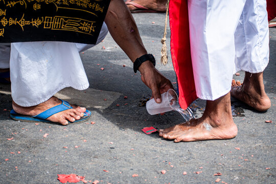Close-up of water being poured onto a devotee's bare feet during the Phuket Vegetarian Festival procession