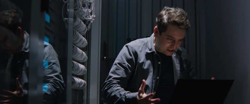 Male Network Engineer Losing Temper While Facing Critical Server Failure in Dark Server Room at Night. IT Burnout, Network Downtime, Cybersecurity Stress, and High Pressure Incident Response.