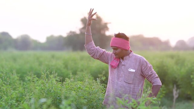 young indian farmer giving happy expression while standing at pigeon pea agriculture field