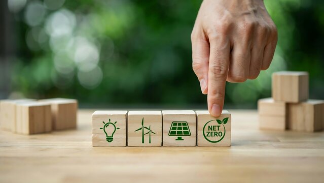 Hand pointing to net zero wooden block representing sustainable energy and environmental protection