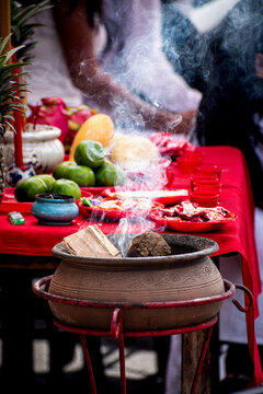Burning incense clay pot and colorful food offerings on a red table at a Taoist vegetarian festival in Thailand