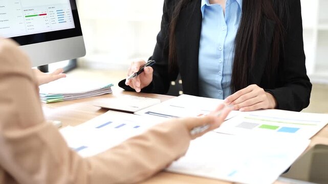 Close up view of businesswomen hands pointing pens at financial charts and documents during strategy meeting in office.