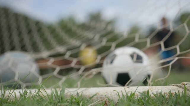 Soccer Balls Inside Goal Net on Green Grass Field During Football Training