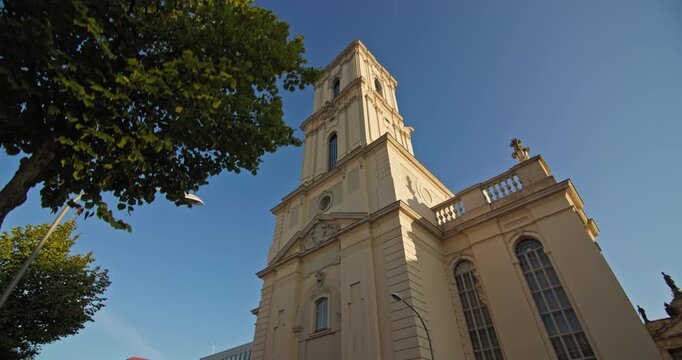 Low-angle view of the Baroque Garrison Church tower in Potsdam, Germany, framed by summer foliage.